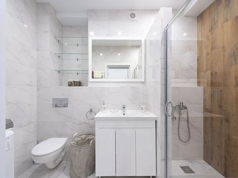 Bad mit Marmorfliesen, wandhängendem WC, Waschtisch und bodengleicher Dusche